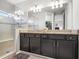Bathroom featuring a dual vanity with granite countertop, dark cabinets, and a glass-enclosed shower at 5717 Village Center Dr, Lithia, FL 33547