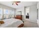 Well-lit bedroom with white comforter, wood dresser, ceiling fan, and curtains, leading to a view of the bathroom at 5717 Village Center Dr, Lithia, FL 33547