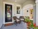 Cozy front porch with seating and decorative accents by the black framed front door at 5717 Village Center Dr, Lithia, FL 33547