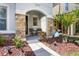 Inviting covered porch with stone accents, seating and decorative landscaping at 5717 Village Center Dr, Lithia, FL 33547