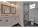 Modern bathroom features a dual sink vanity, a marble-tiled shower, and black and white tile flooring at 6097 Vermont Ave, New Port Richey, FL 34653