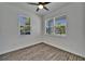 Bedroom featuring two windows with blinds, a ceiling fan, and wood-look flooring at 6097 Vermont Ave, New Port Richey, FL 34653