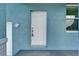 Close-up of a white front door with a textured blue exterior, combining security with subtle elegance at 6097 Vermont Ave, New Port Richey, FL 34653