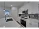 Kitchen with white cabinets, granite countertops, stainless steel appliances, and a modern tile backsplash at 6097 Vermont Ave, New Port Richey, FL 34653