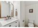 Stylish half-bath featuring a modern vanity with a wooden-framed mirror and white paneled walls at 7705 S Sparkman St, Tampa, FL 33616
