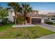 Two-story home with green lawn, landscaping, palm trees, a two-car garage, and neutral colored exterior at 7705 S Sparkman St, Tampa, FL 33616
