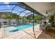 Screened in pool and travertine deck featuring tropical landscaping and ceiling fan at 7705 S Sparkman St, Tampa, FL 33616