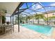 Screened in pool with a table and chairs on the travertine deck and tropical landscaping at 7705 S Sparkman St, Tampa, FL 33616