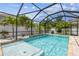 Screened pool with clear blue water, rock waterfall, and well maintained landscaping at 7705 S Sparkman St, Tampa, FL 33616