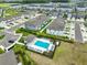 Aerial view of a well-planned community with a pool, clubhouse, and neatly arranged townhomes and landscaping at 7709 Imagination Pl, Wesley Chapel, FL 33545