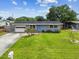 Well-maintained single-story home with a lush front lawn and a pop of color from the blue front door at 8528 Iris Ave, Seminole, FL 33777
