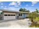 Charming single-story home features an attached garage, light blue accents, and a well-maintained front yard at 8528 Iris Ave, Seminole, FL 33777