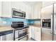 Bright kitchen with stainless steel appliances, sleek granite countertops, and white cabinets for storage at 8528 Iris Ave, Seminole, FL 33777