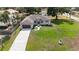 An aerial view showcases this home with a long driveway, two-car garage, and a green, expansive front lawn at 9416 Bullfrog Court, Gibsonton, FL 33534