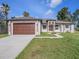 Charming single-story home with a beautiful, dark wood garage door and walkway at 9416 Bullfrog Court, Gibsonton, FL 33534