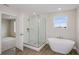 Modern bathroom with glass enclosed shower, freestanding tub, tile flooring, and natural light at 9955 Surrey Rose Dr, San Antonio, FL 33576