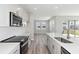 Kitchen boasts stainless appliances, and sleek, light gray cabinetry with a view to living room at 9961 Surrey Rose Dr, San Antonio, FL 33576