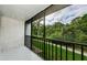 View from balcony with black railing, offering views of lush greenery and nearby walking path at 1170 Pine Ridge W Cir # C2, Tarpon Springs, FL 34688