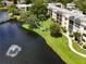 Aerial view of lakeside condo buildings with lush landscaping, a fountain and a small bridge at 14130 Rosemary Ln # 3215, Largo, FL 33774