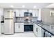 A view of the kitchen with stainless steel appliances and light grey cabinets and granite countertop at 14130 Rosemary Ln # 3215, Largo, FL 33774