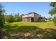Expansive backyard with lush greenery and the rear of the house featuring a screened-in porch at 14282 Coronado Dr, Spring Hill, FL 34609