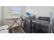 Well-equipped laundry room with a sleek, modern black washer and dryer set, plus storage and ironing board at 14282 Coronado Dr, Spring Hill, FL 34609