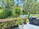 Well-maintained backyard featuring mature trees, manicured shrubs, and a patio with a grill at 16219 Nottingham Park Way, Tampa, FL 33647