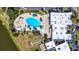 Aerial view features a community pool with blue umbrellas, nearby building, and bocce ball court at 1908 Canterbury Ln # 28, Sun City Center, FL 33573