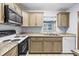 A cozy kitchen with a granite countertop, a double sink, and tan-colored cabinets at 1908 Canterbury Ln # 28, Sun City Center, FL 33573