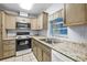 Charming kitchen featuring stainless steel appliances, ample granite countertops, double sinks, and tan colored cabinets at 1908 Canterbury Ln # 28, Sun City Center, FL 33573