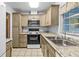 Well-lit kitchen featuring an oven, microwave, double sinks, granite countertops, and tan colored cabinets at 1908 Canterbury Ln # 28, Sun City Center, FL 33573