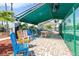 Outdoor seating area under a green awning, featuring colorful chairs and a brick-paved patio at 1908 Canterbury Ln # 28, Sun City Center, FL 33573