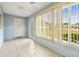 Bright sunroom with tile floors, paneled blue walls, a ceiling fan, and large windows at 1908 Canterbury Ln # 28, Sun City Center, FL 33573