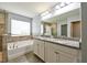 Primary bathroom featuring double vanities, granite countertop, tiled floors, and a separate tub and shower at 19200 Roseate Dr, Lutz, FL 33558