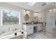 Bright bathroom with a double vanity, granite counters, and a large soaking tub with tub to ceiling window at 2933 W Alline Ave, Tampa, FL 33611