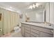 Well-lit bathroom featuring a shower with curtain and a granite-topped vanity with modern fixtures at 31643 Colada Drift Way, Wesley Chapel, FL 33545