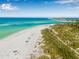 Expansive aerial view of a pristine white sand beach with turquoise waters and lush green vegetation at 321 N Boulevard Of The Presidents, Sarasota, FL 34236