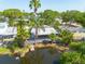 Waterfront home featuring a wooden deck, dock, and screened porch with lush tropical landscaping at 328 Tallahassee Ne Dr, St Petersburg, FL 33702