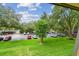 Scenic parking lot with a view of a building, mature trees, and a vibrant blue sky at 36750 Us 19 N # 07208, Palm Harbor, FL 34684