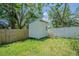 Backyard storage shed with small ramp and door, surrounded by green grass and wood fences at 402 12Th Sw St, Ruskin, FL 33570