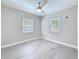 Neutral bedroom with light gray walls, a ceiling fan, two windows, and gray wood-look flooring at 4291 Neptune Se Dr, St Petersburg, FL 33705