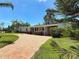Inviting single-story home with a circular brick driveway and verdant landscaping under a clear blue sky at 4291 Neptune Se Dr, St Petersburg, FL 33705