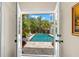 Inviting pool area viewed through open doors, surrounded by lush greenery and patio furniture at 455 18Th Ne Ave, St Petersburg, FL 33704