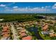 An aerial shot showcases a home near a pond, set against a backdrop of lush greenery and a distant view of the ocean at 4611 Grand Preserve Pl, Palm Harbor, FL 34684