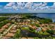 Aerial view of a residential area featuring houses with red-tile roofs surrounding a tranquil lake with a fountain at 4611 Grand Preserve Pl, Palm Harbor, FL 34684