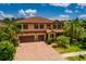 Beautiful two-story home featuring a three-car garage, red shutters, and a well-maintained brick driveway at 4611 Grand Preserve Pl, Palm Harbor, FL 34684