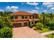 Beautiful two-story home featuring a three-car garage, red shutters, and a well-maintained brick driveway at 4611 Grand Preserve Pl, Palm Harbor, FL 34684