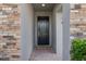 Inviting front entry with a modern black door, brick floor, and stone veneer wall at 4690 Coachford Dr, Wesley Chapel, FL 33543