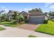 Charming home featuring a well manicured lawn, brick driveway, gray exterior paint, and beautiful stone accents at 4690 Coachford Dr, Wesley Chapel, FL 33543
