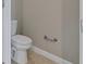 Standard toilet with beige tile floor and a metal towel bar on the wall at 4690 Coachford Dr, Wesley Chapel, FL 33543